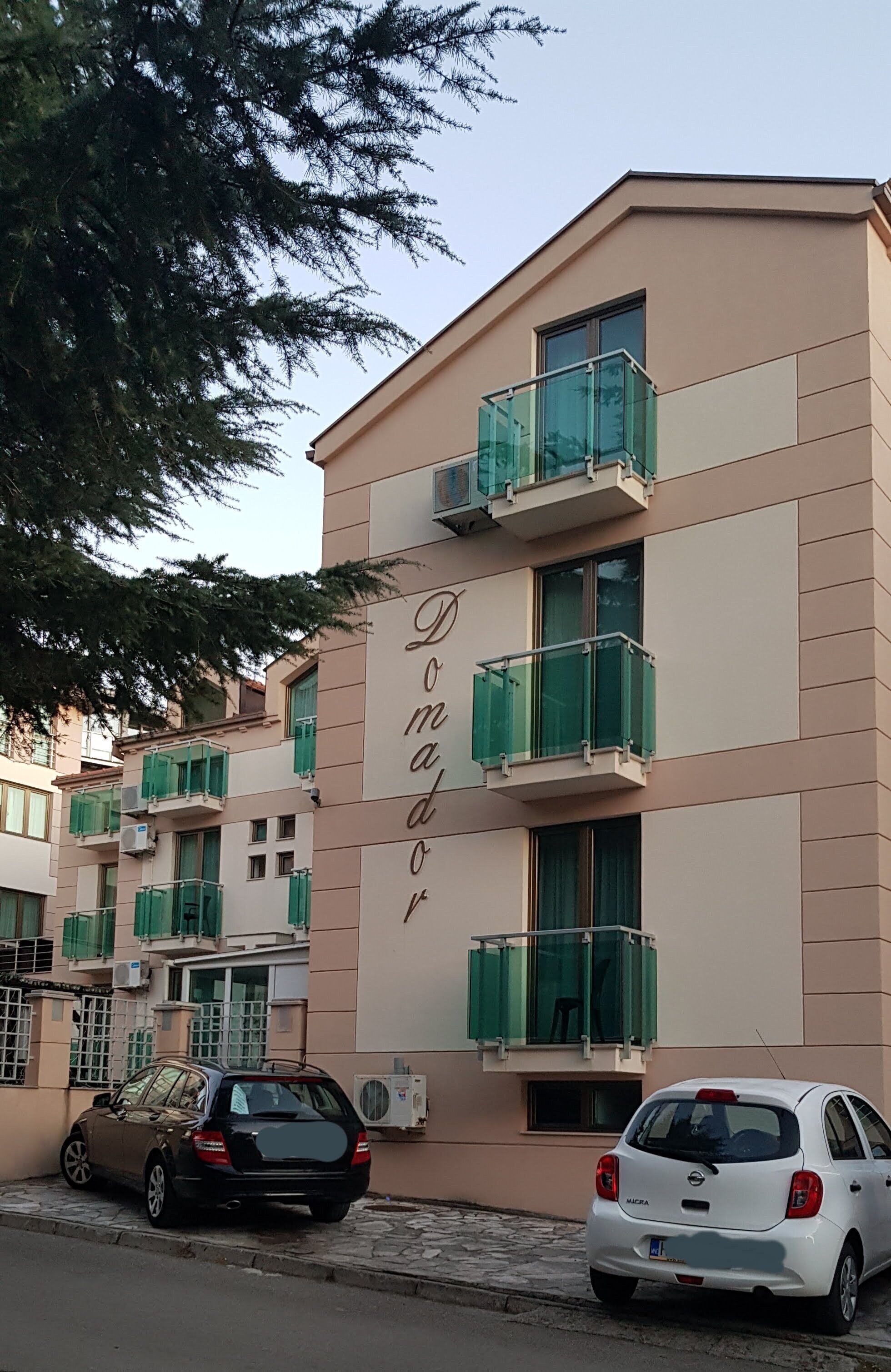 A multi-story building with balconies and a sign that reads "Domador".