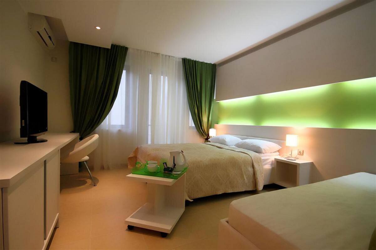Une chambre d’hôtel comprenant un lit, une table de chevet, un bureau avec une chaise, une télévision et une balance.