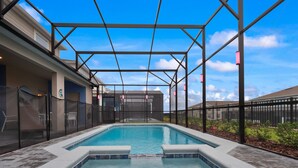 A swimming pool with a covered area, surrounded by a fence and a view of buildings in the background. - PROMO Elegant 9 BR Villa, Pool/Spa, Resort - by Blue Sky Villas (Davenport)