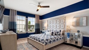 A bedroom with a bed, a ceiling fan, a nightstand, a lamp, and a window with curtains. - PROMO Elegant 9 BR Villa, Pool/Spa, Resort - by Blue Sky Villas (Davenport)