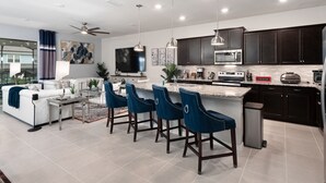 A modern kitchen with dark cabinets, stainless steel appliances, and a marble countertop. - PROMO Elegant 9 BR Villa, Pool/Spa, Resort - by Blue Sky Villas (Davenport)