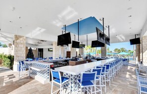 Un vaste espace bar extérieur doté de plusieurs coins salon, d’un îlot central équipé du matériel nécessaire au service des boissons et d’un sapin de Noël.