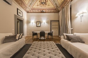 Ein Hotelzimmer mit Essbereich, zwei Sofas, einem Knopfhocker und einer Kristallleuchtre.
