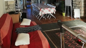 Een gezellige woonkamer met een bank, een eettafel gedekt voor een maaltijd en een stenen open haard.
