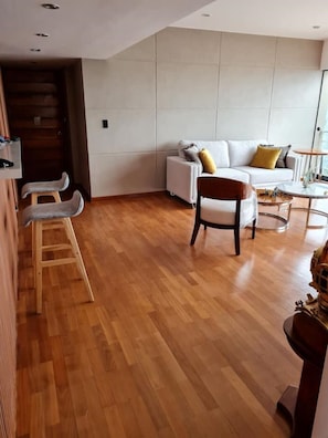 A modern living room with a white sofa, wooden floor, and a small wooden ladder. - VIP apartment in Miraflores, Lima. DeLux. (Miraflores)
