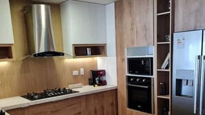 A modern kitchen with wooden cabinets, a stainless steel range hood, built-in oven, and a refrigerator. - VIP apartment in Miraflores, Lima. DeLux. (Miraflores)