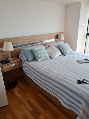 A neatly made bed with striped bedding, a wooden headboard, and a bedside table with a lamp.