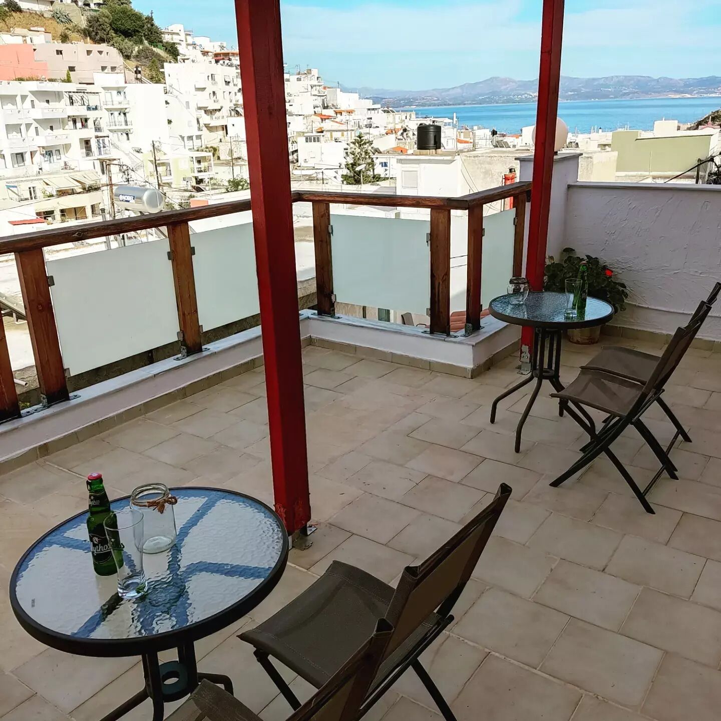 A balcony with a table and chairs, overlooking a coastal cityscape.