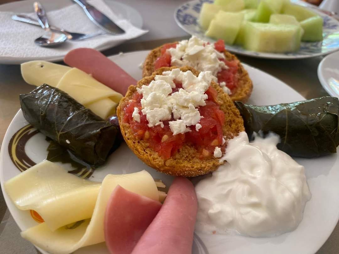 A plate with stuffed grape leaves, cheese, and a dollop of yogurt.