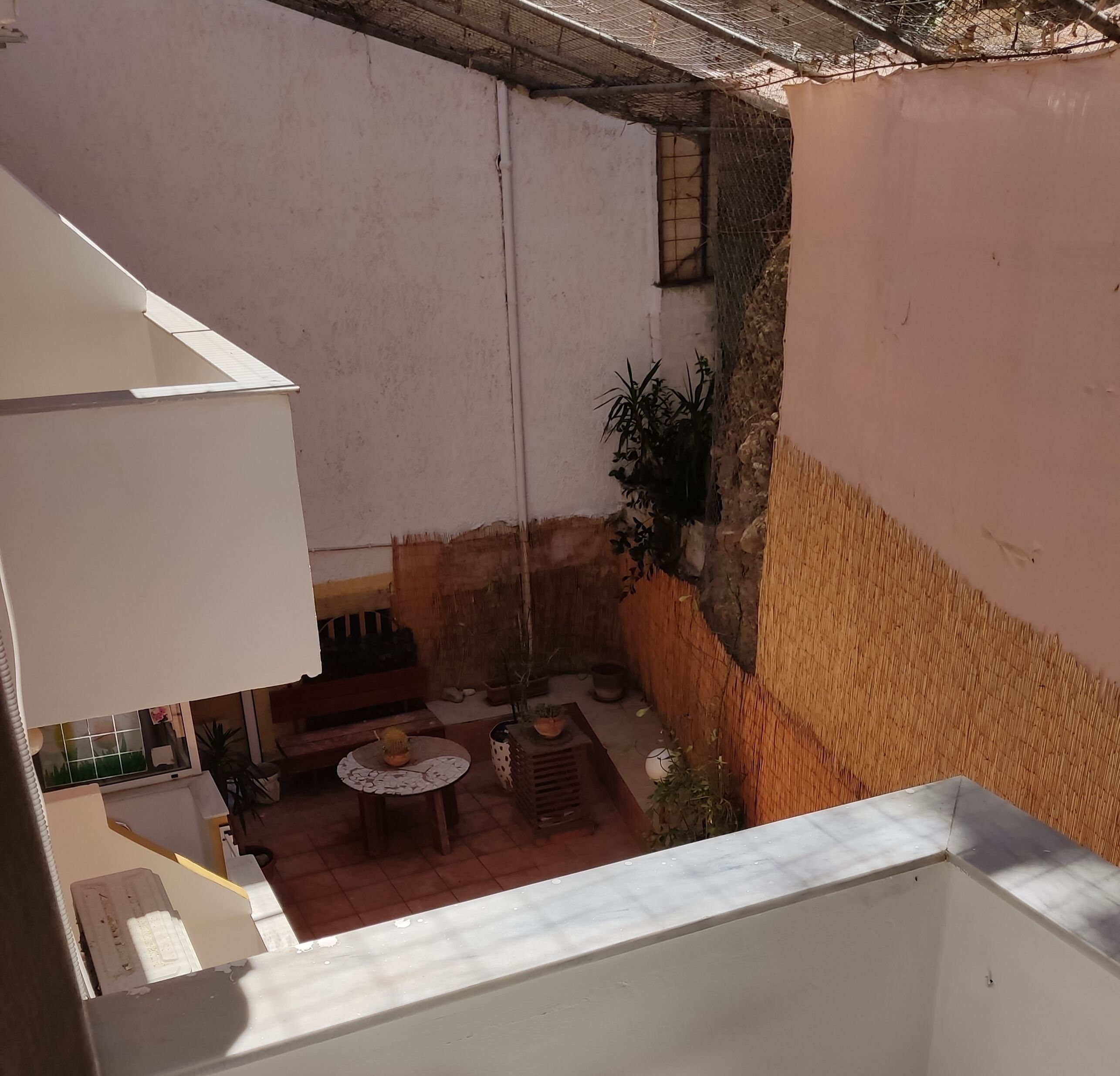 A courtyard with a seating area, a hanging plant, and a view of the surrounding area.