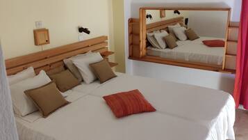Camera d'albergo con un letto grande, una testiera in legno, un comodino, uno specchio e un condizionatore d'aria a parete.