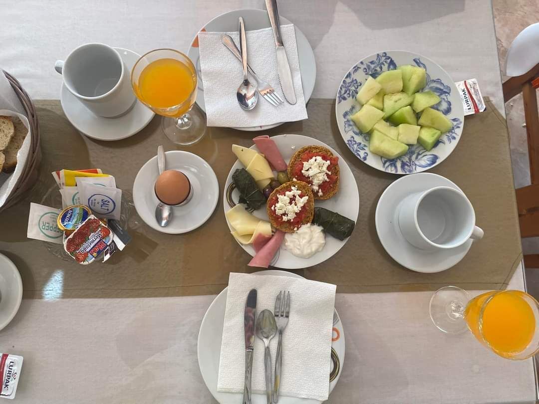 A breakfast table with plates of food, including toast, eggs, and fruit, and a glass of orange juice.
