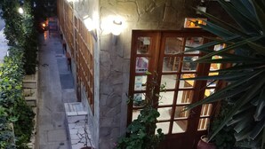 A staircase leading to a building with a tiled roof and a wooden door. There are potted plants on the ground floor.