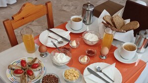 A breakfast table with plates of toast, eggs, and fruit, along with coffee and juice.