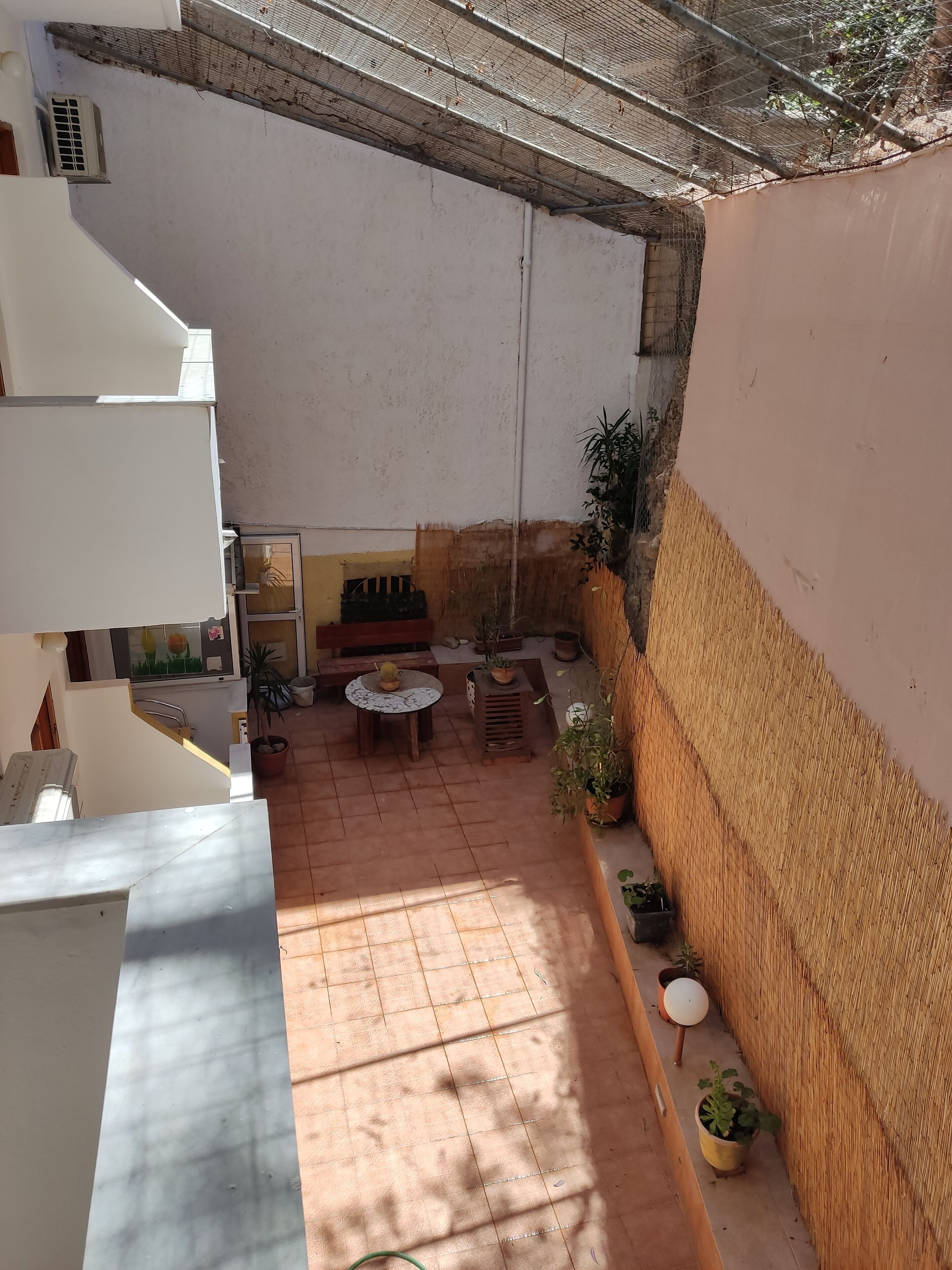 A courtyard with a tiled floor, a seating area with a table and chairs, and potted plants.