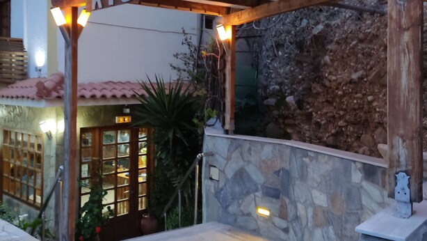 A wooden pergola entrance with the name 'Kissandros' illuminated above.