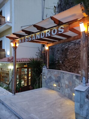 A wooden pergola entrance with the name 'Kissandros' illuminated above. - Hotel Kissandros (Agios Vasileios)