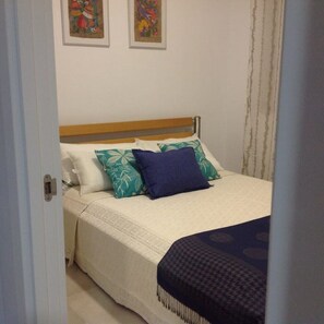 A bedroom with a bed, a wooden headboard, and a white wall.