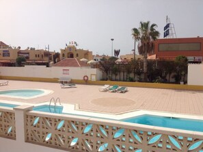 Uma área de piscina no terraço com duas piscinas, espreguiçadeiras e um flutuador.