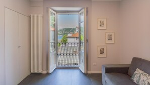 An interior view of a room with a balcony, a radiator, a sofa, and framed pictures on the wall.