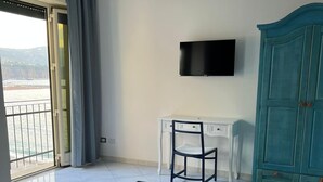 Una habitación de hotel con cama, escritorio, televisor y armario.