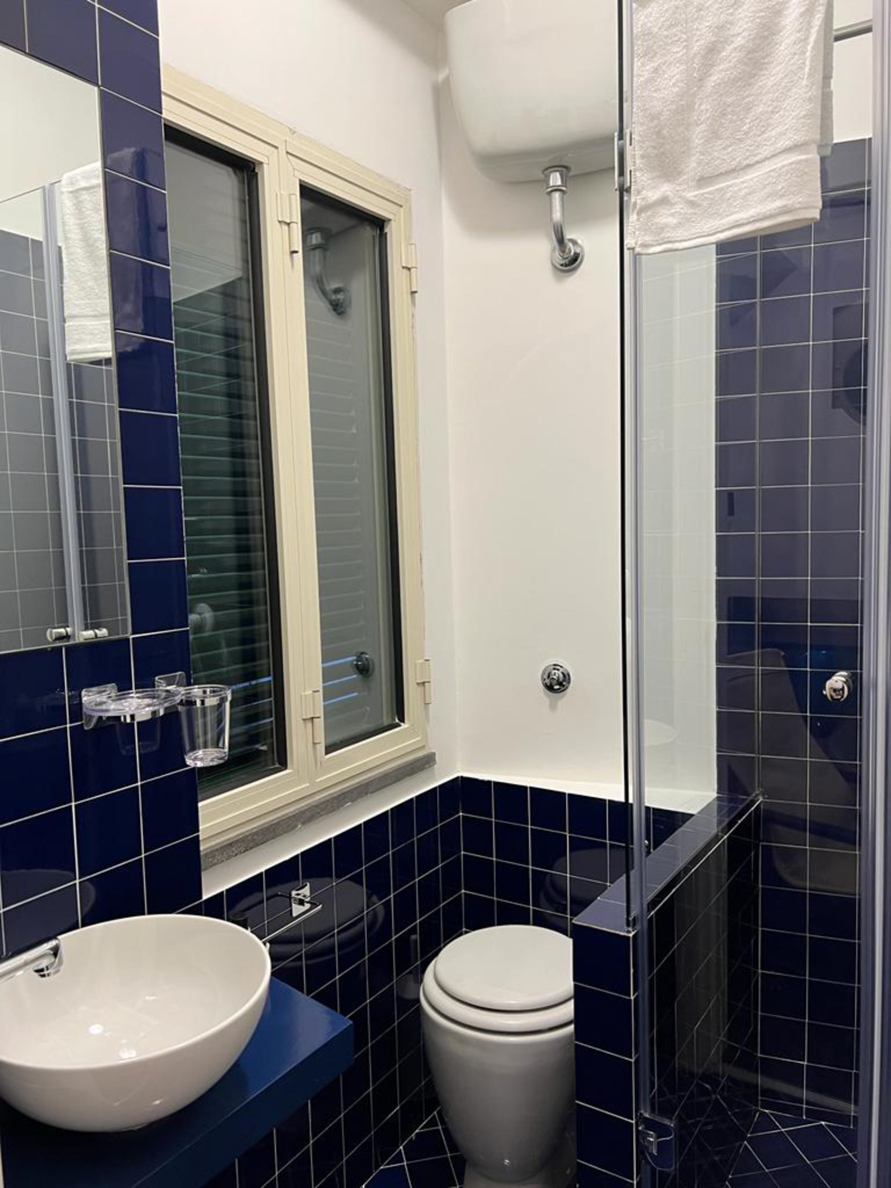 Un baño con lavamanos blanco, inodoro y cabina de ducha de cristal.