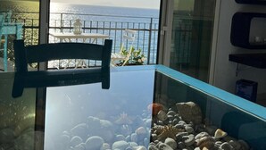 Un balcón con una mesa de vidrio, una silla y un acuario con rocas y una estrella de mar.