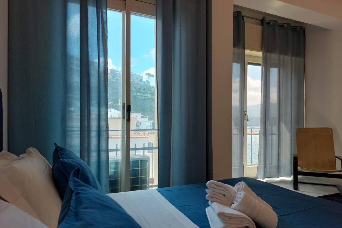 Een hotelkamer met een bed, een stoel en uitzicht op een balkon met een hekwerk.