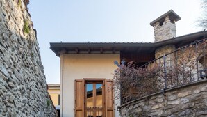 A stone building with a wooden door and window shutters. - San Fedele Apartments (Como)