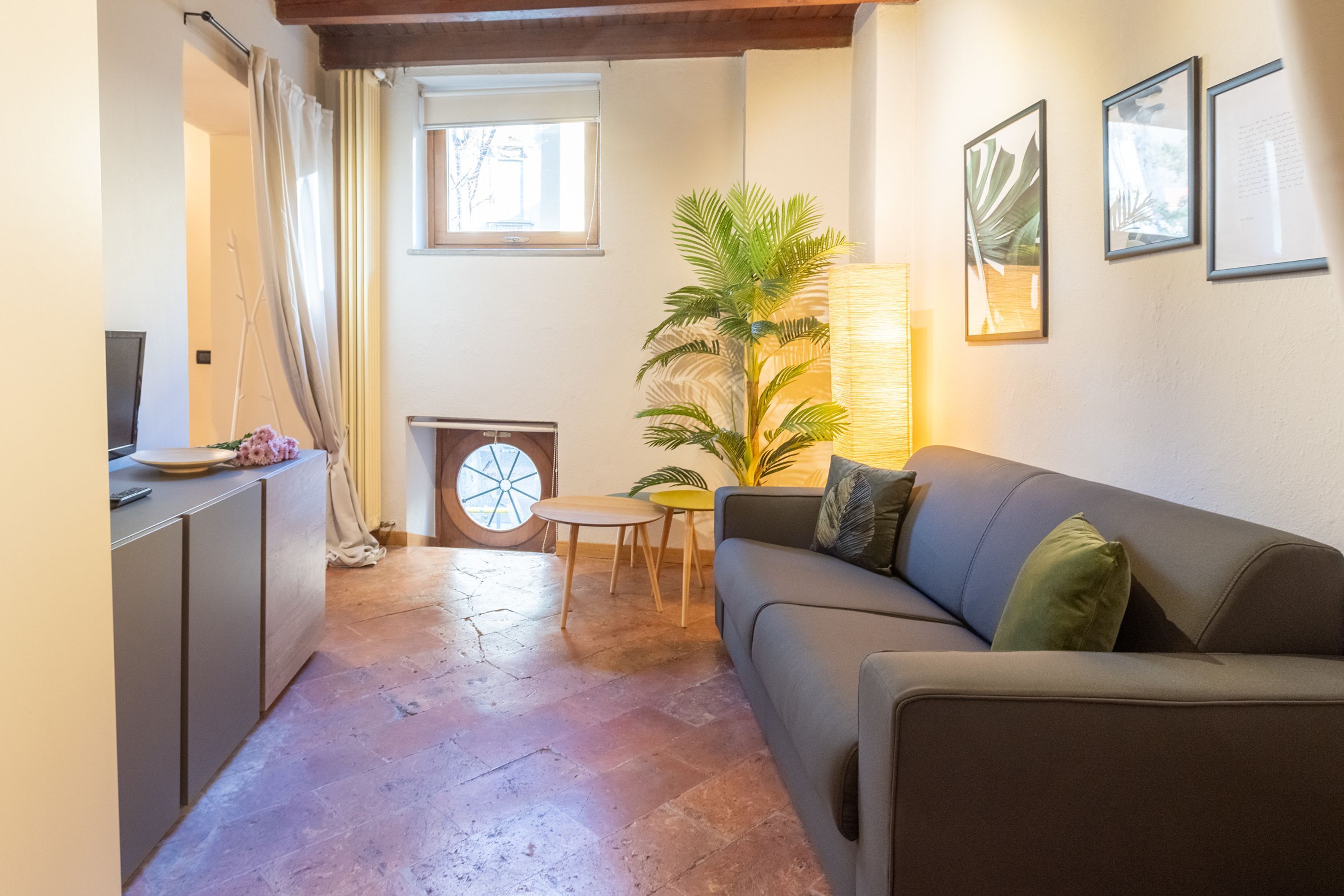 A cozy living area with a sofa, a small table, a potted plant, and a fireplace.