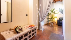 A cozy living area with a wooden bench, a white vase with flowers, and a table with a plant and a lamp. - San Fedele Apartments (Como)