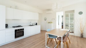 A modern kitchen with white cabinets, a wooden dining table, and a chandelier. - Mezzegra Apartments in Tremezzo (Tremezzina)