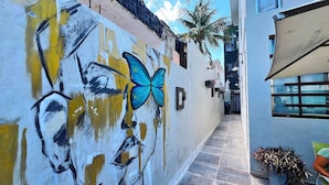 A narrow alleyway with a mural of a butterfly and abstract art on the wall.