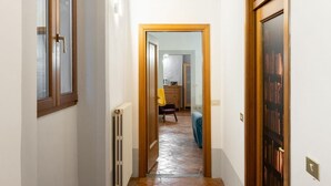 A narrow hallway with a tiled floor, wooden doors, and a ceiling with exposed beams. - Toscanella Apartment (Florence)