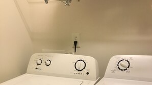 Eine Waschmaschine und ein Trockner in einem Gerät, mit Bedienknöpfen und einer Steckdose an der Wand.
