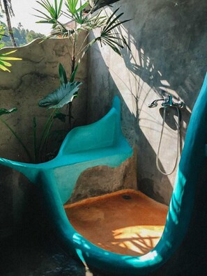 A bathroom with a blue bathtub, a shower, and a plant. - Pondok Apsari 2 (Sukasada)