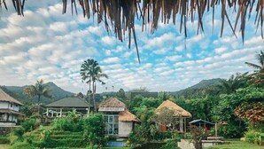 A rural landscape with terraced fields, thatched-roof huts, and a clear sky. - Pondok Apsari 2 (Sukasada)
