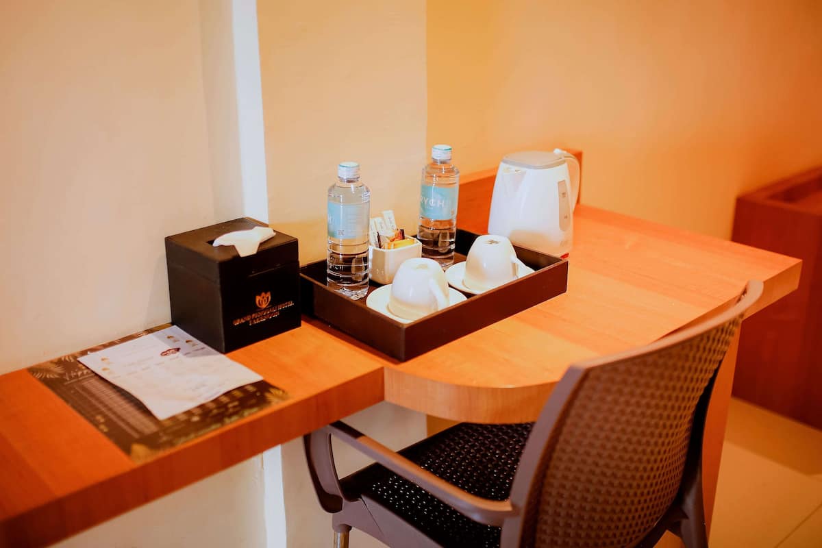 Un bureau dans une chambre d’hôtel, sur lequel se trouve un plateau avec des bouteilles d’eau, une machine à café et une boîte de mouchoirs.