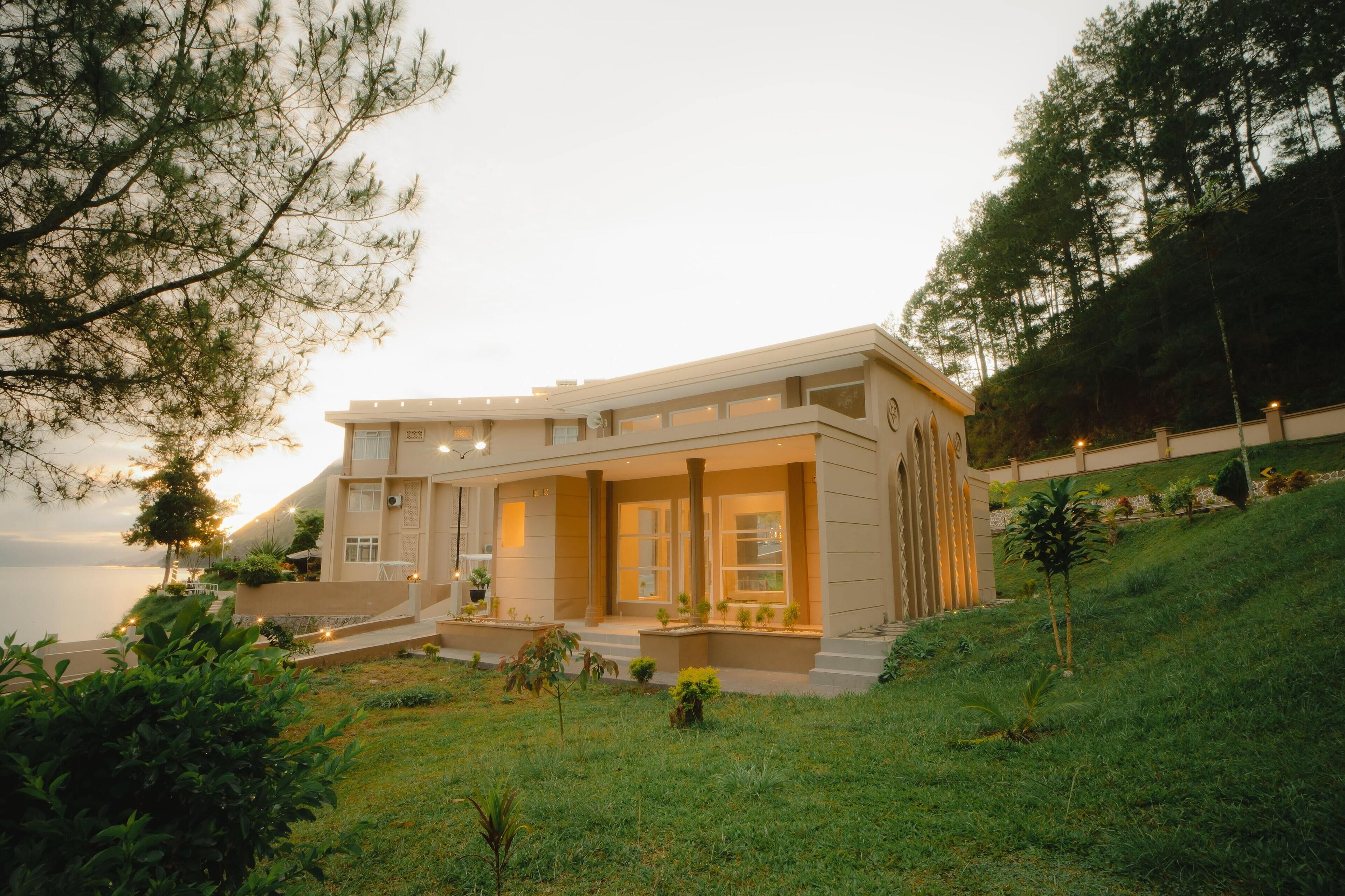 A modern building with a flat roof, large windows, and a well-maintained lawn.