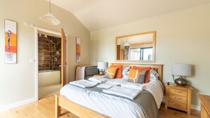 Un dormitorio moderno con una cama de madera, una mesita de noche, un espejo y un baño con ducha y bañera.