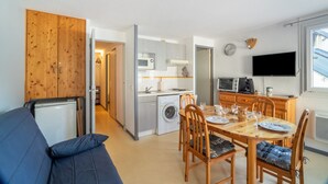 Kompakti oleskelutila, jossa on ruokailualue, pieni keittiö ja sohva.