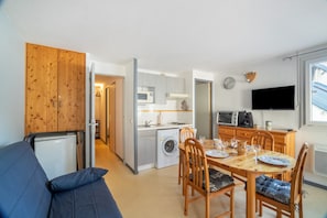 A compact living space with a dining area, kitchenette, and a sofa. - Le Maintenon - One Bedroom Apartment, Sleeps 4 (Barèges)
