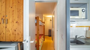 Pieni, käytännöllinen keittiö, jossa on mikroaaltouuni, pesuallas ja puukaapit.