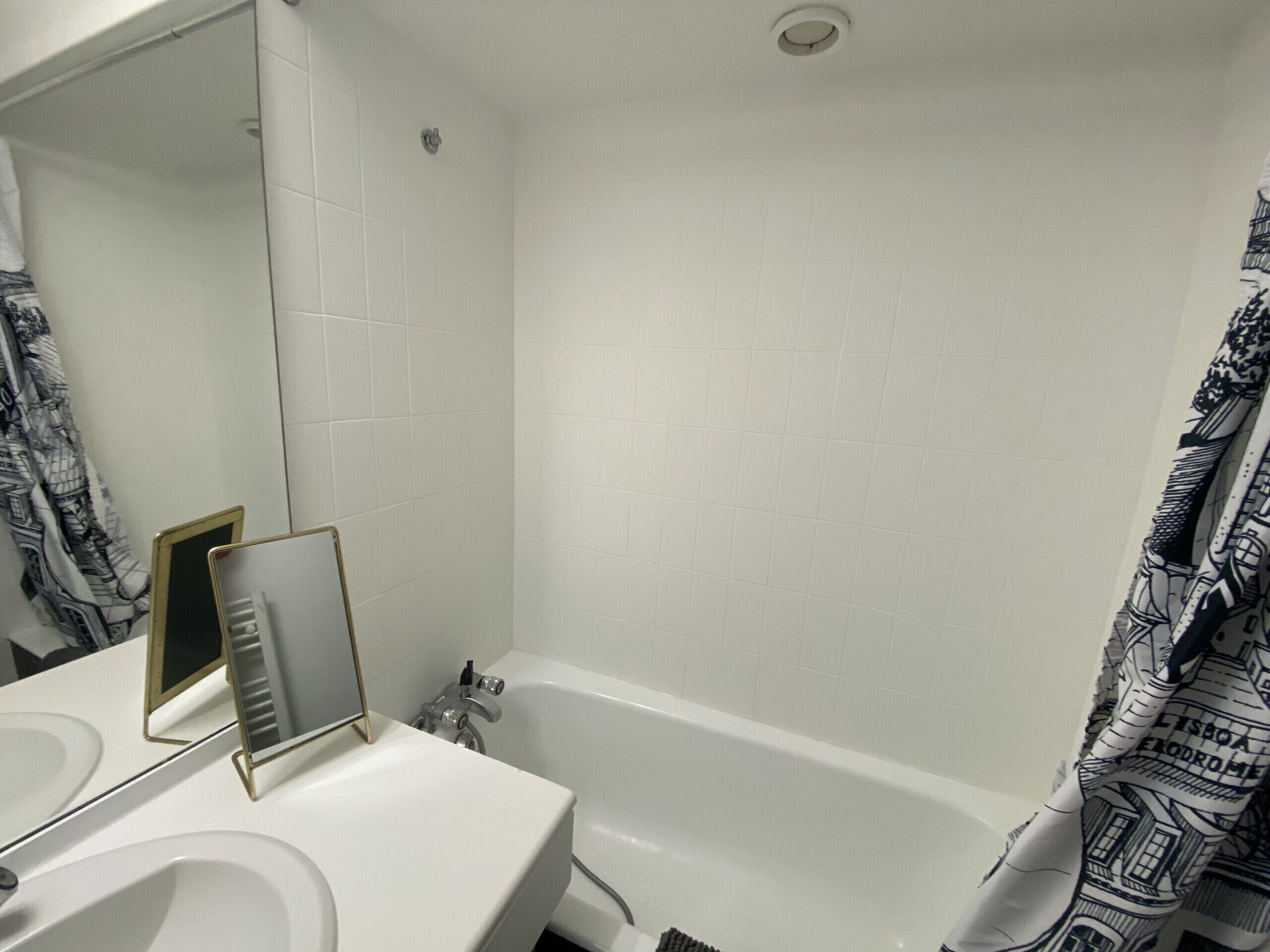 A bathroom with a white sink, a mirror, and a bathtub.