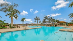 A swimming pool with multiple lanes, surrounded by palm trees and lounge chairs. - Modern Waterfront Home in Artesia | Pool/Gym (Naples)