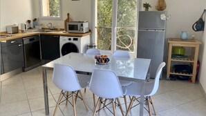 A modern kitchen with a dining table, chairs, and a refrigerator. - A little gem in lush greenery - sea view (lumio)