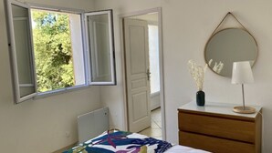 A bedroom with a bed, a dresser, a mirror, and a window with an open shutter. - A little gem in lush greenery - sea view (lumio)