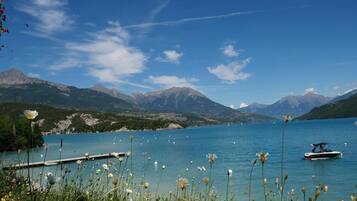 Un lac paisible, avec des montagnes en arrière-plan, un quai et un bateau.