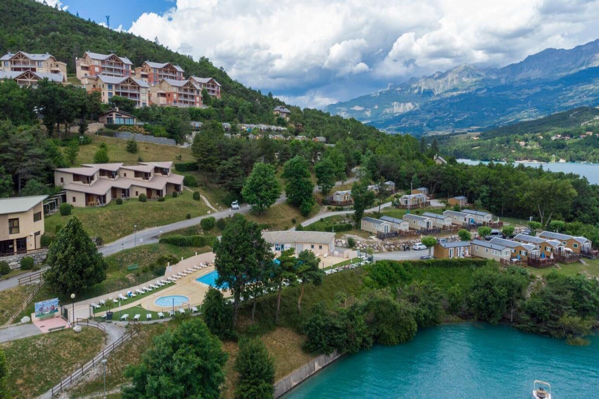 Un resort con varias construcciones, una piscina y un lago.
