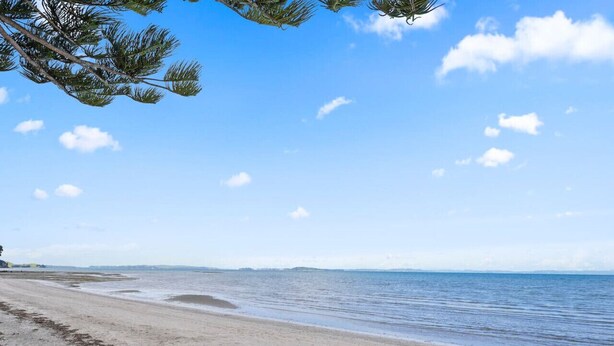 Une plage avec un ciel dégagé et une mer calme.